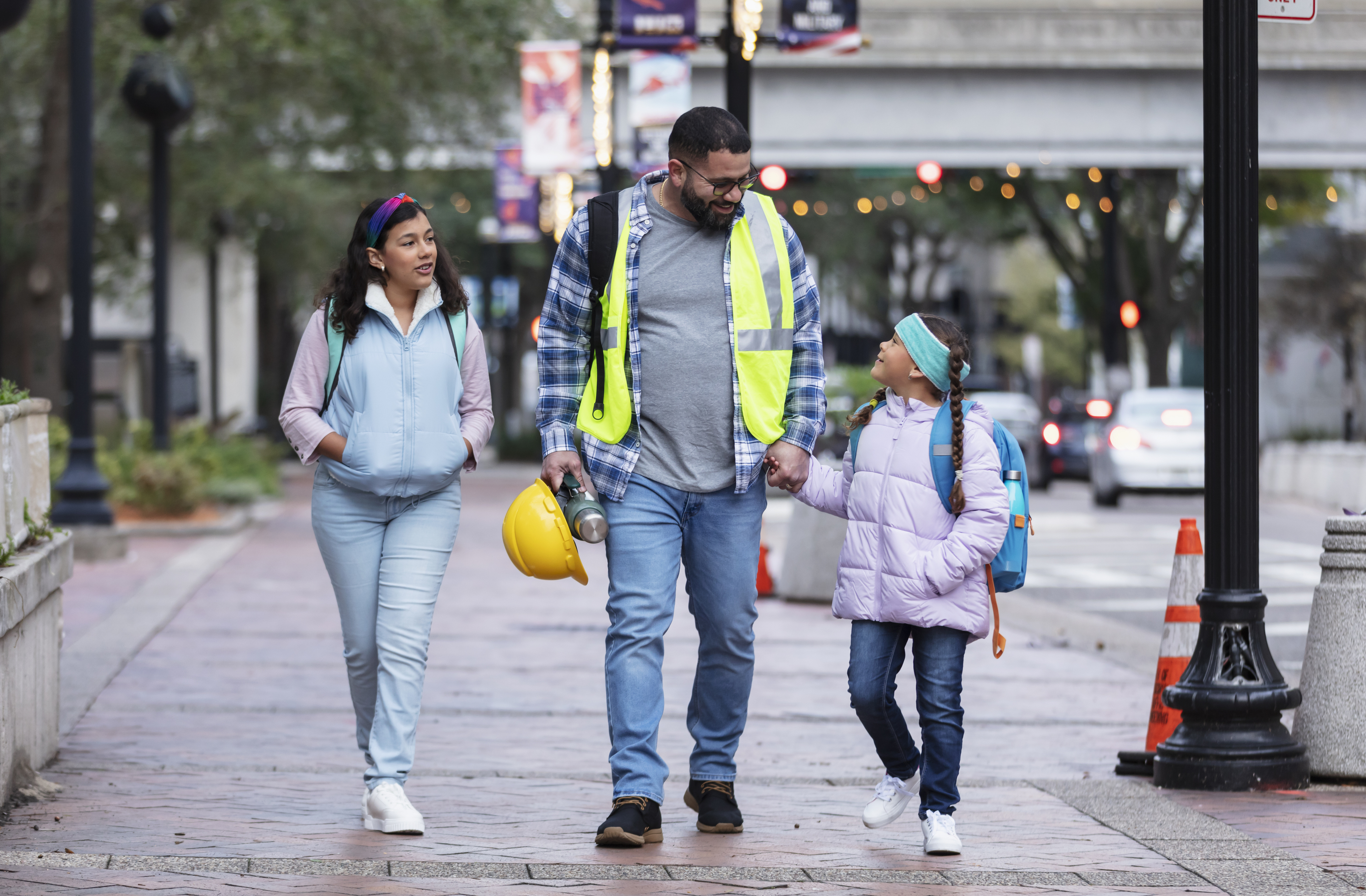 Construction worker taking daughters to school in city