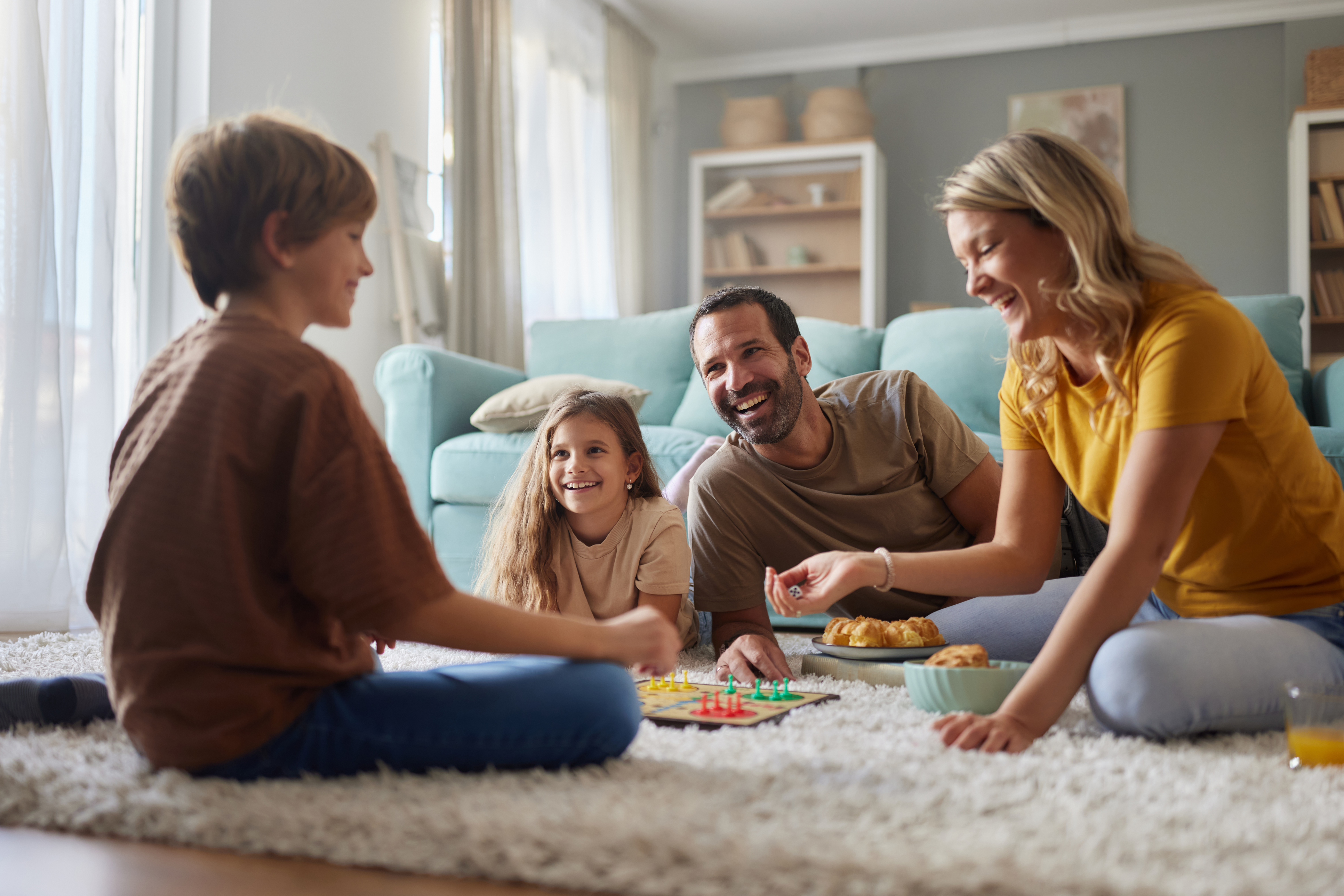 Happy parents and kids playing on carpet at home.