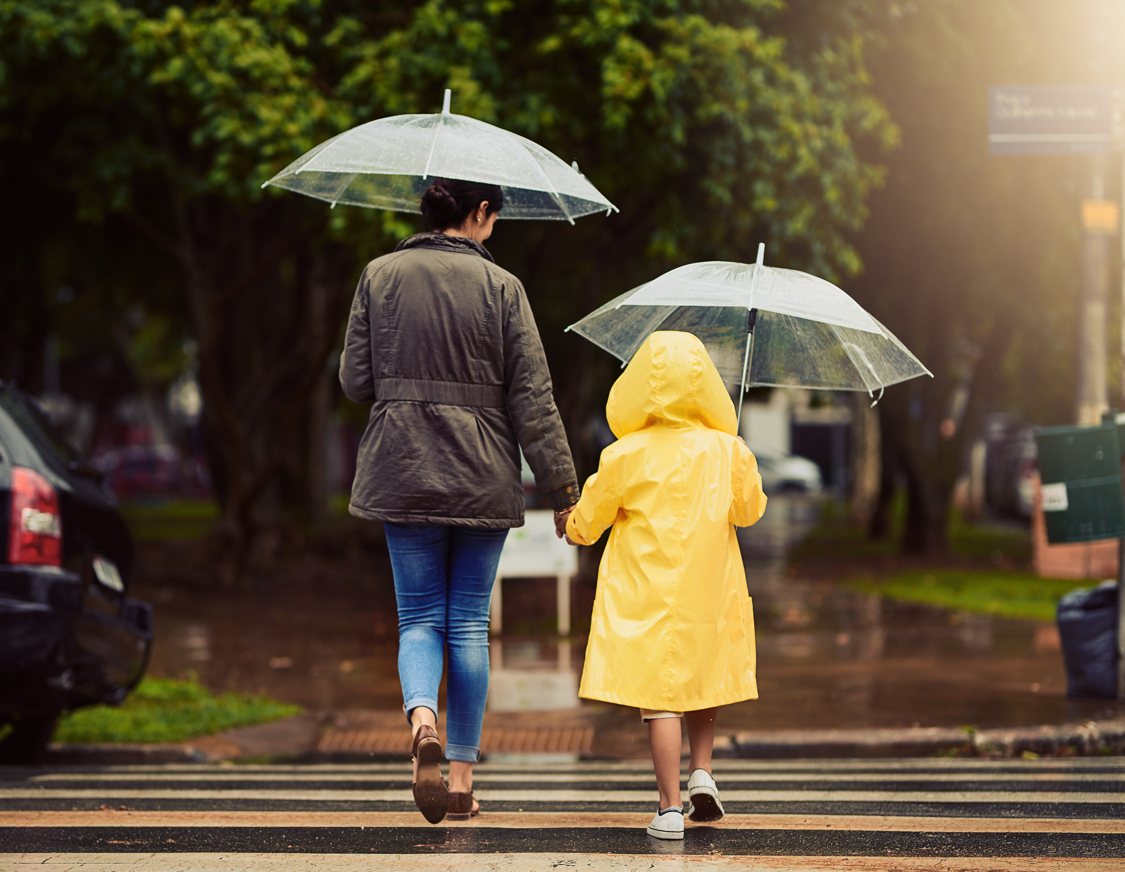 Mom and son holding hands and walking in the rain outside under an umbrella